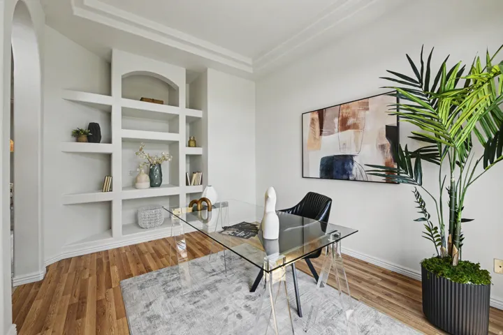 Built-in shelving unit with an arched alcove, crown molding, wood-finish flooring, and a wide entryway arch