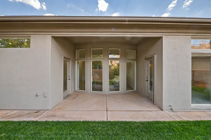 Covered patio featuring a concrete surface, stucco exterior, multiple glass doors, and a series of floor-to-ceiling bay windows