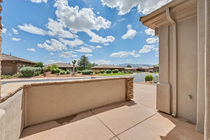 Outdoor patio featuring a concrete surface, a low stone-clad wall, and stucco exterior