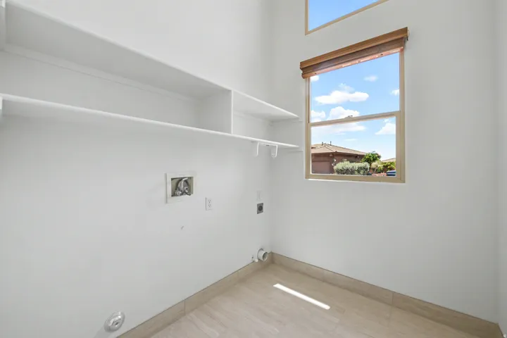 Utility room featuring built-in shelving, a large window, and light-toned tile flooring