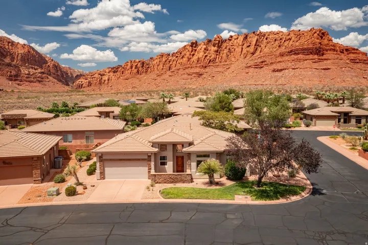 Single-story residence featuring a tan stucco exterior, integrated two-car garage, and a front yard with mature landscaping