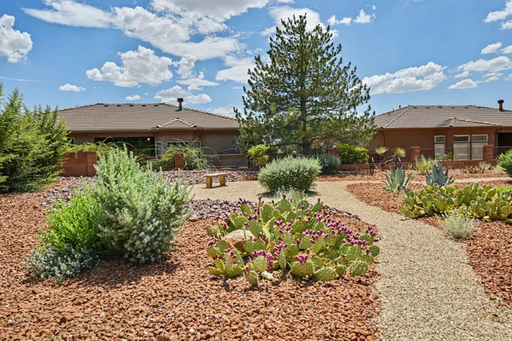 Landscaped backyard featuring gravel pathways, desert plantings, mature shrubbery, and a large tree