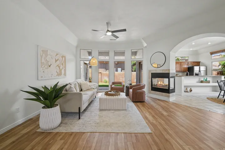 Bright living area featuring wood-finish flooring, a contemporary ceiling fan, and a gas fireplace with a tiled surround