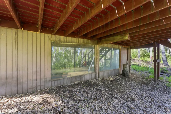 Under-deck area featuring exposed wooden joists, a panel-sided foundation wall, and two large fixed-pane windows