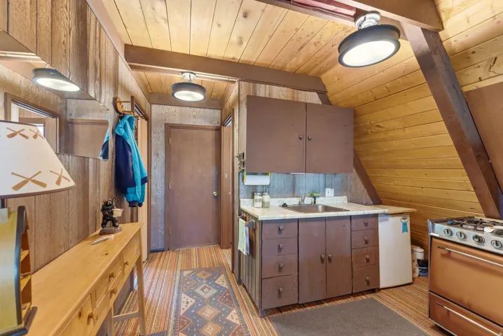 Compact kitchen area featuring wood-finish cabinetry, a single basin sink, and an integrated refrigerator