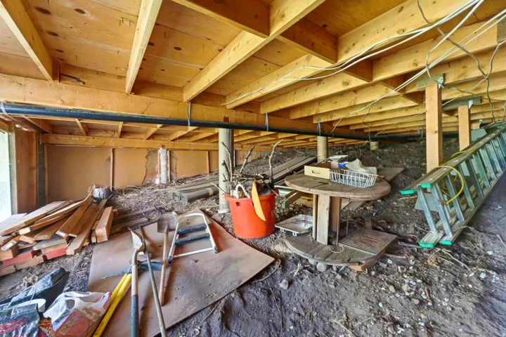 Exposed wooden joists and subflooring define this under-structure space