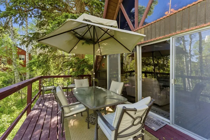 Expansive wooden deck featuring perimeter railing, sliding glass door access to the interior, and a partial A-frame architectural style visible