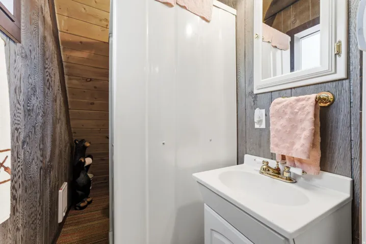 Bathroom featuring a white vanity with an integrated sink, brass-finish faucet, and a wall-mounted mirror with a white frame