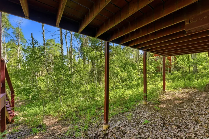 Open-air underdeck space featuring a natural floor and wooden support beams