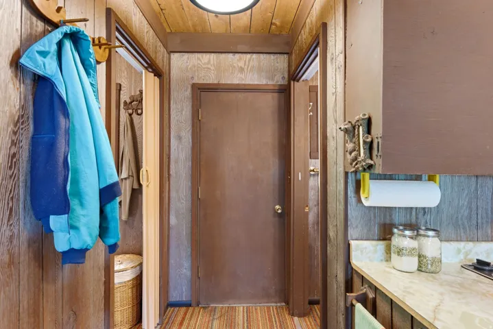 Entryway featuring wood-finish paneling, a flush-mount ceiling light, and a solid-core door