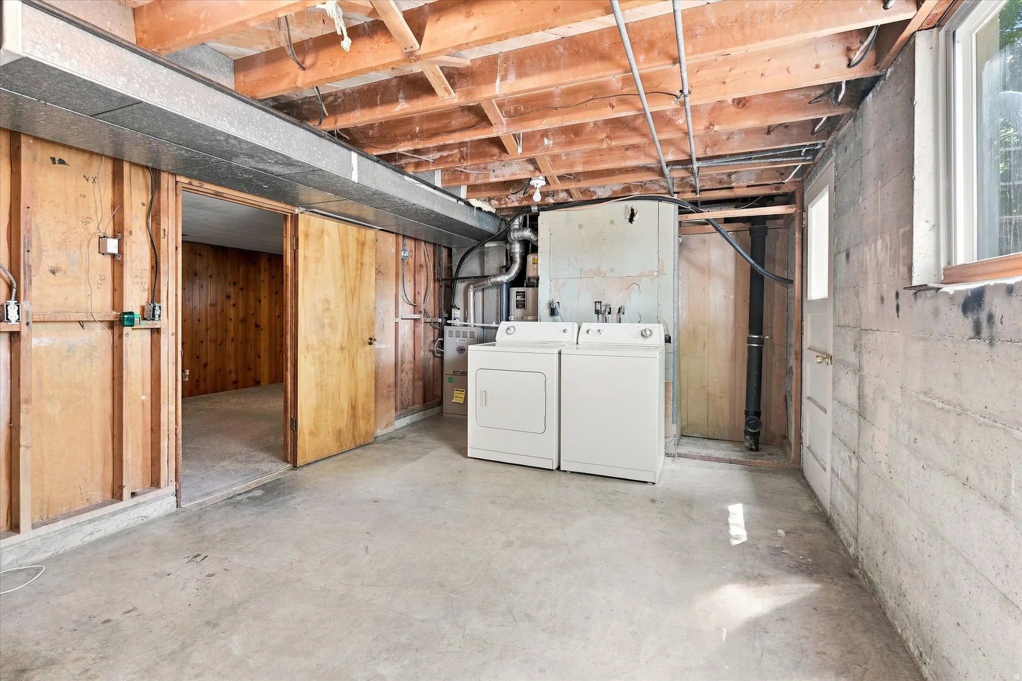 Utility area with a concrete floor, exposed ceiling joists, and a window
