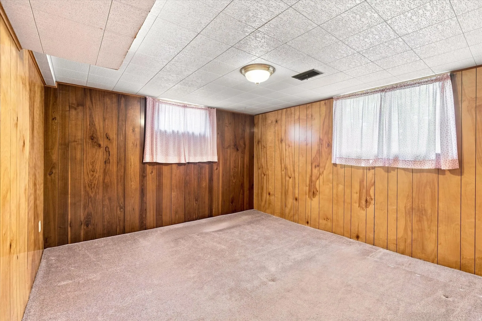 Room featuring wood-paneled walls, carpeted flooring, and a drop ceiling with recessed lighting