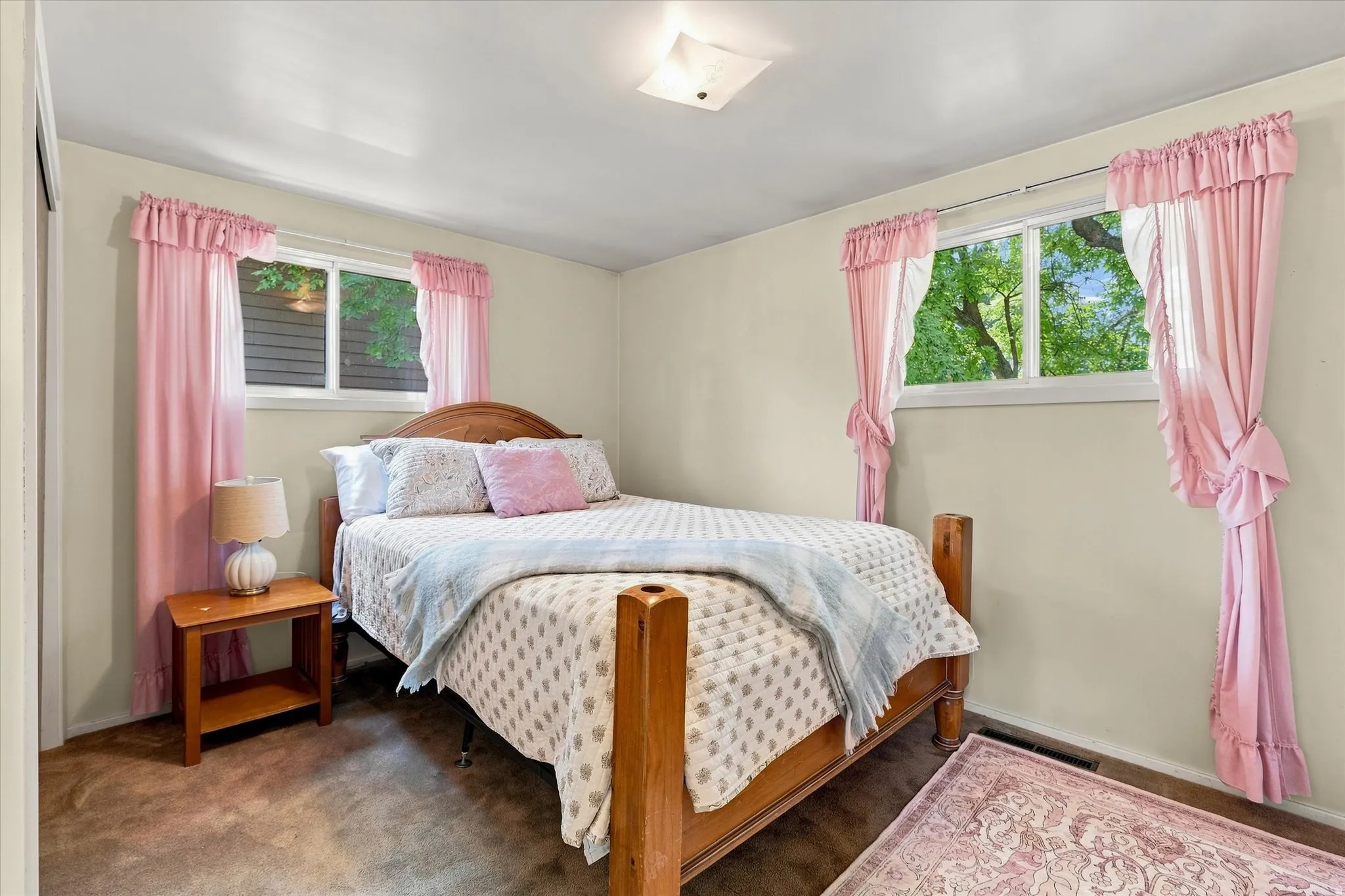 Bedroom featuring two windows, neutral wall tones, and carpeted flooring