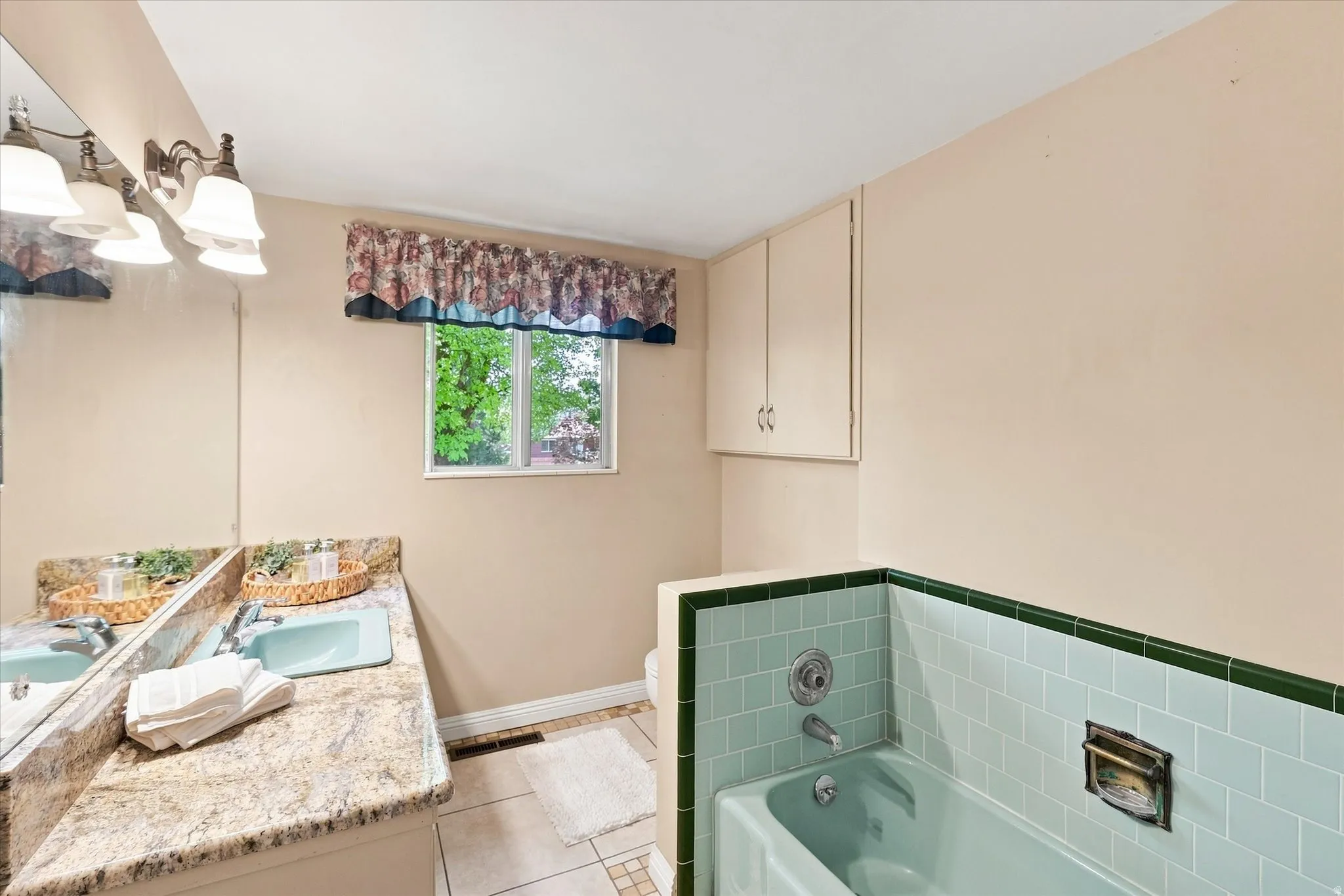 Bathroom featuring a granite-finish countertop, dual sinks, and built-in cabinetry