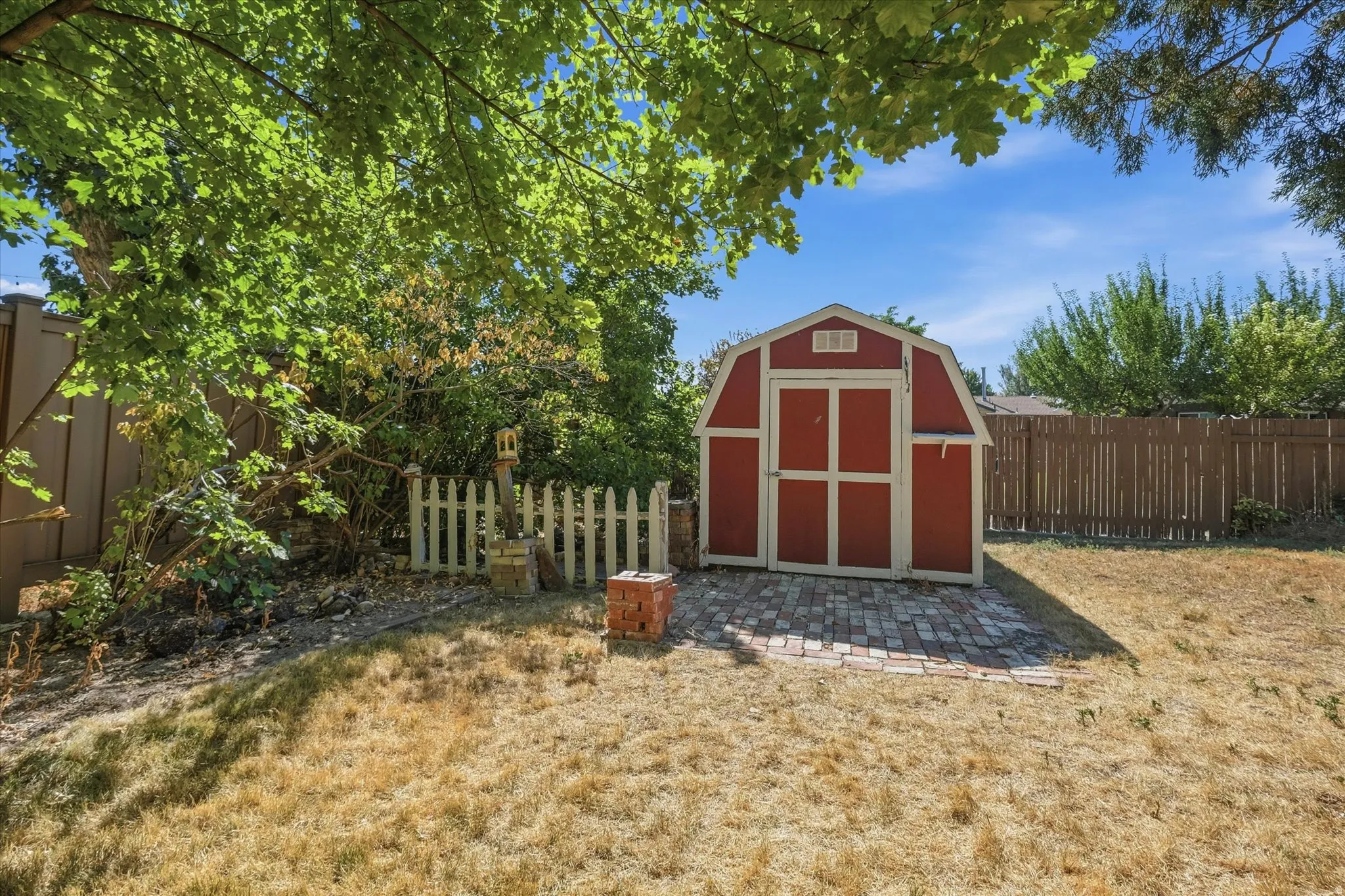 Backyard featuring a red barn-style shed on a brick paver foundation