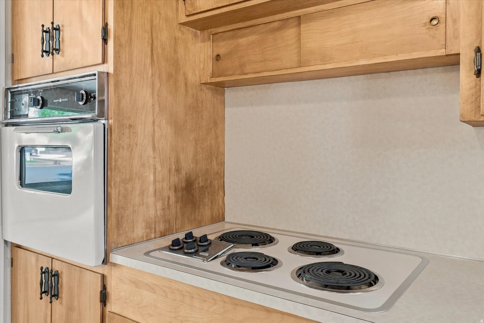 Kitchen featuring wood cabinetry, integrated vintage wall oven, and built-in vintage electric stovetop with four coil burners