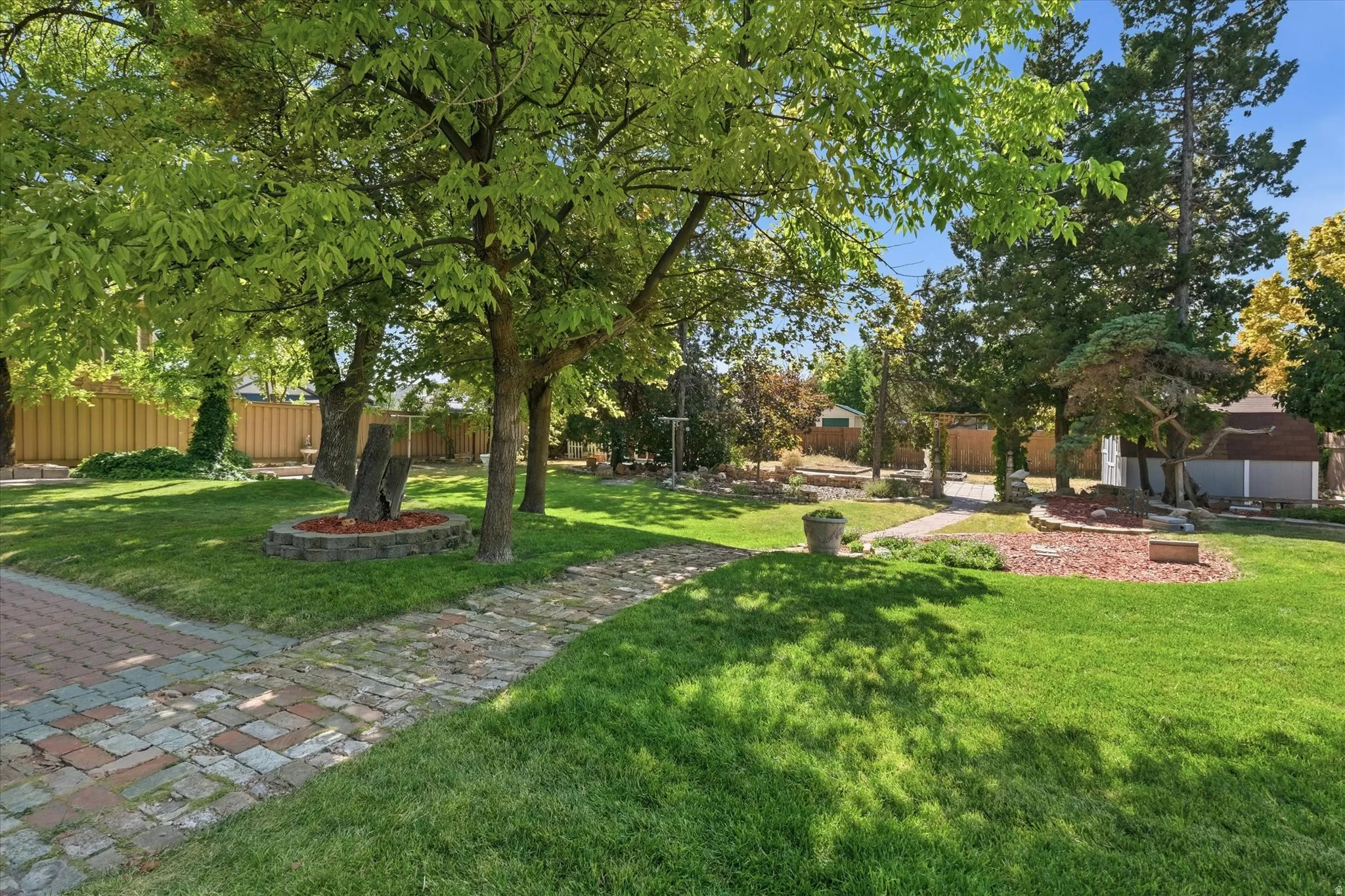 Expansive lawn area featuring mature trees and a brick paver pathway