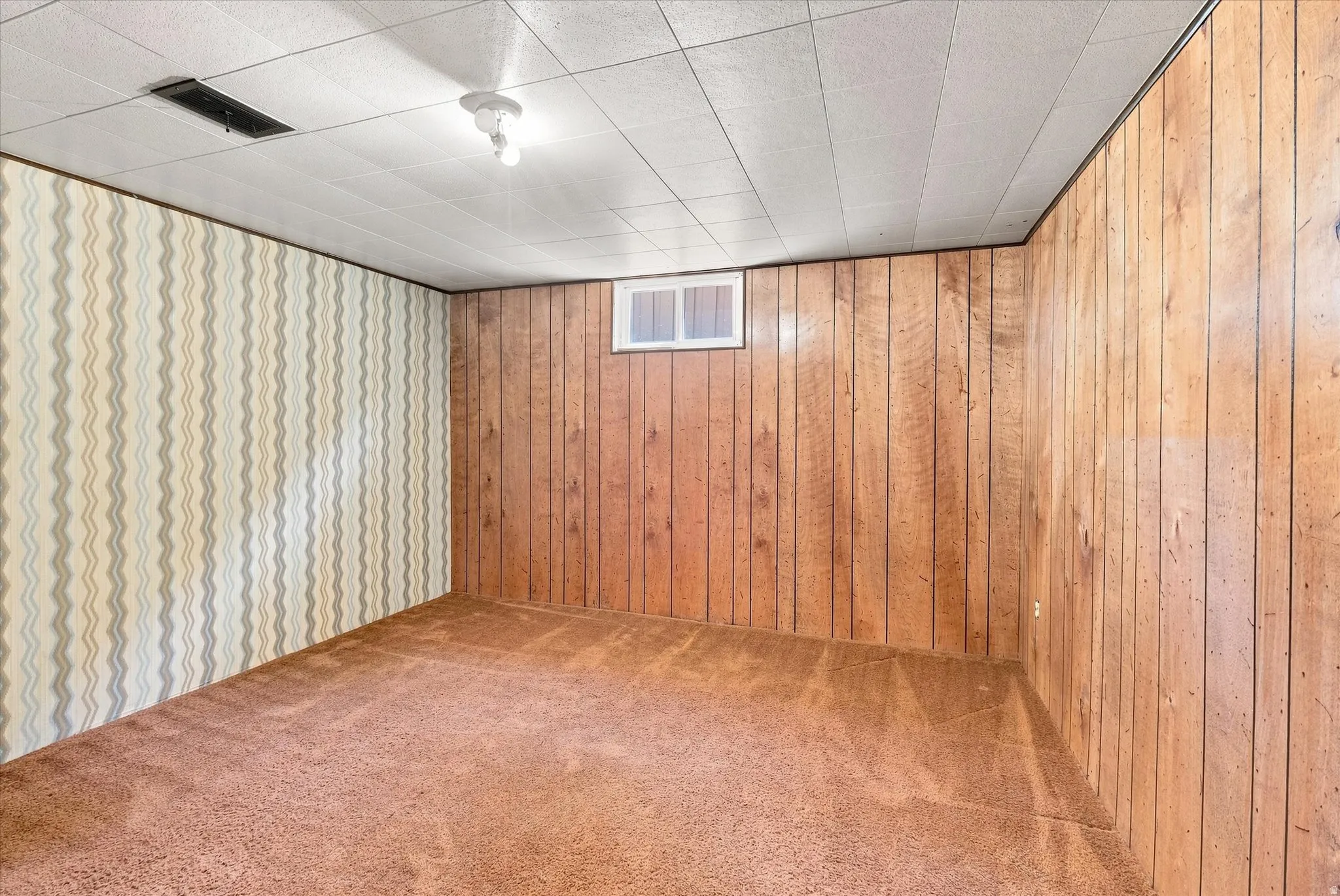 Interior room featuring a textured ceiling, a patterned wallpaper accent wall, and wood paneling on the remaining walls