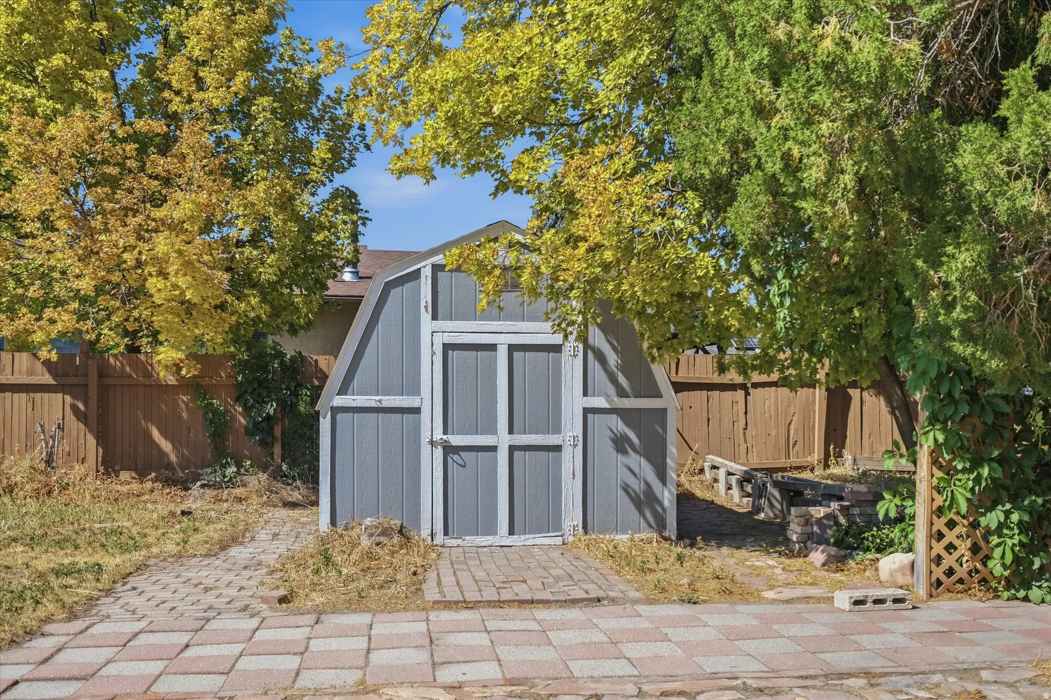 Barn-style shed with double doors, set on a paver stone patio