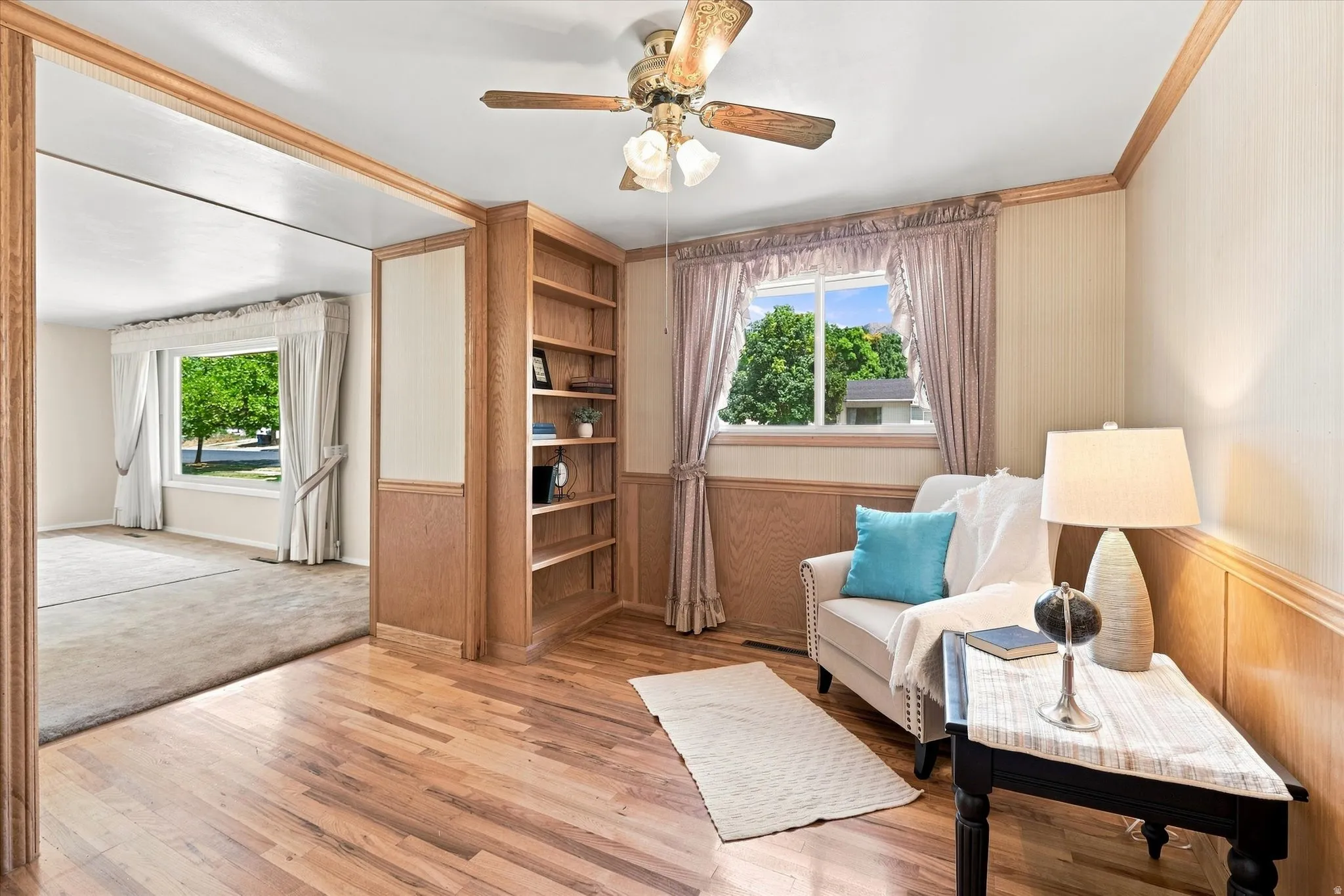 Hardwood flooring throughout the foreground room features a built-in bookcase with shelving