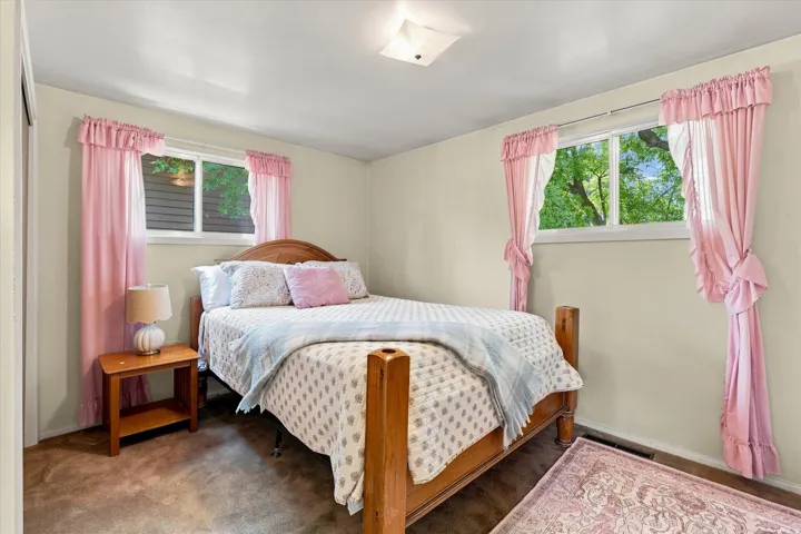 Bedroom featuring two windows, neutral wall tones, and carpeted flooring