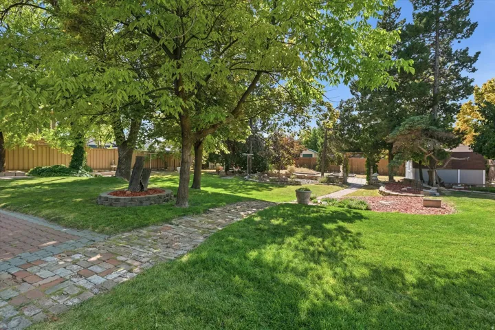 Expansive lawn area featuring mature trees and a brick paver pathway
