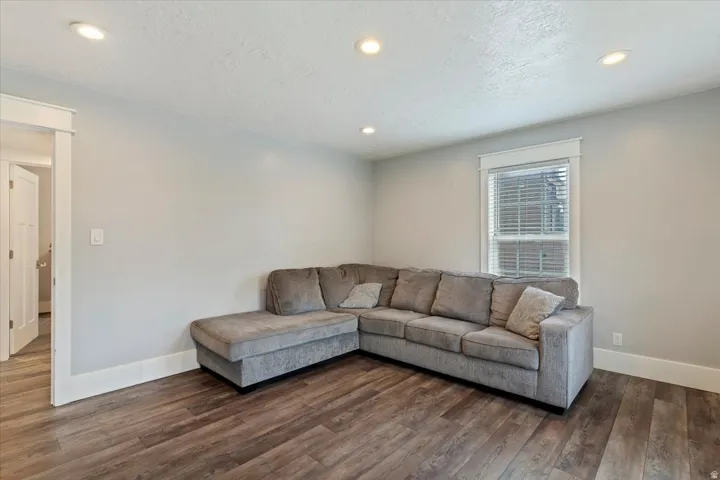 Spacious room featuring wood-finish flooring, recessed lighting, a window with blinds, light gray walls, and white trim