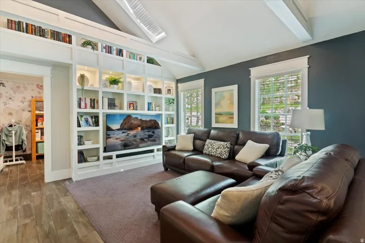 Sophisticated entertainment space showcasing vaulted ceilings with skylights, custom built-in cabinetry with integrated media center, and premium leather seating arrangements
