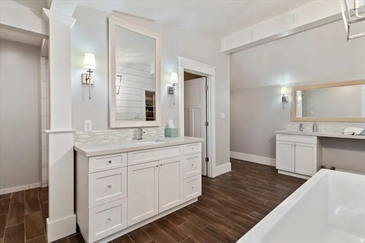 Spa-inspired primary bathroom showcasing a white cabinetry vanity with dual sinks, marble subway tile backsplash, and polished nickel fixtures
