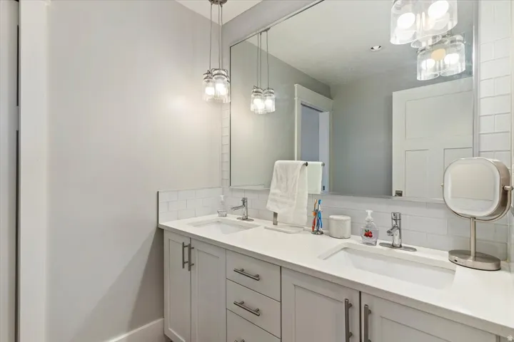 Spa-inspired primary bathroom featuring a dual-sink vanity with white cabinetry, white quartz countertops, and polished chrome hardware