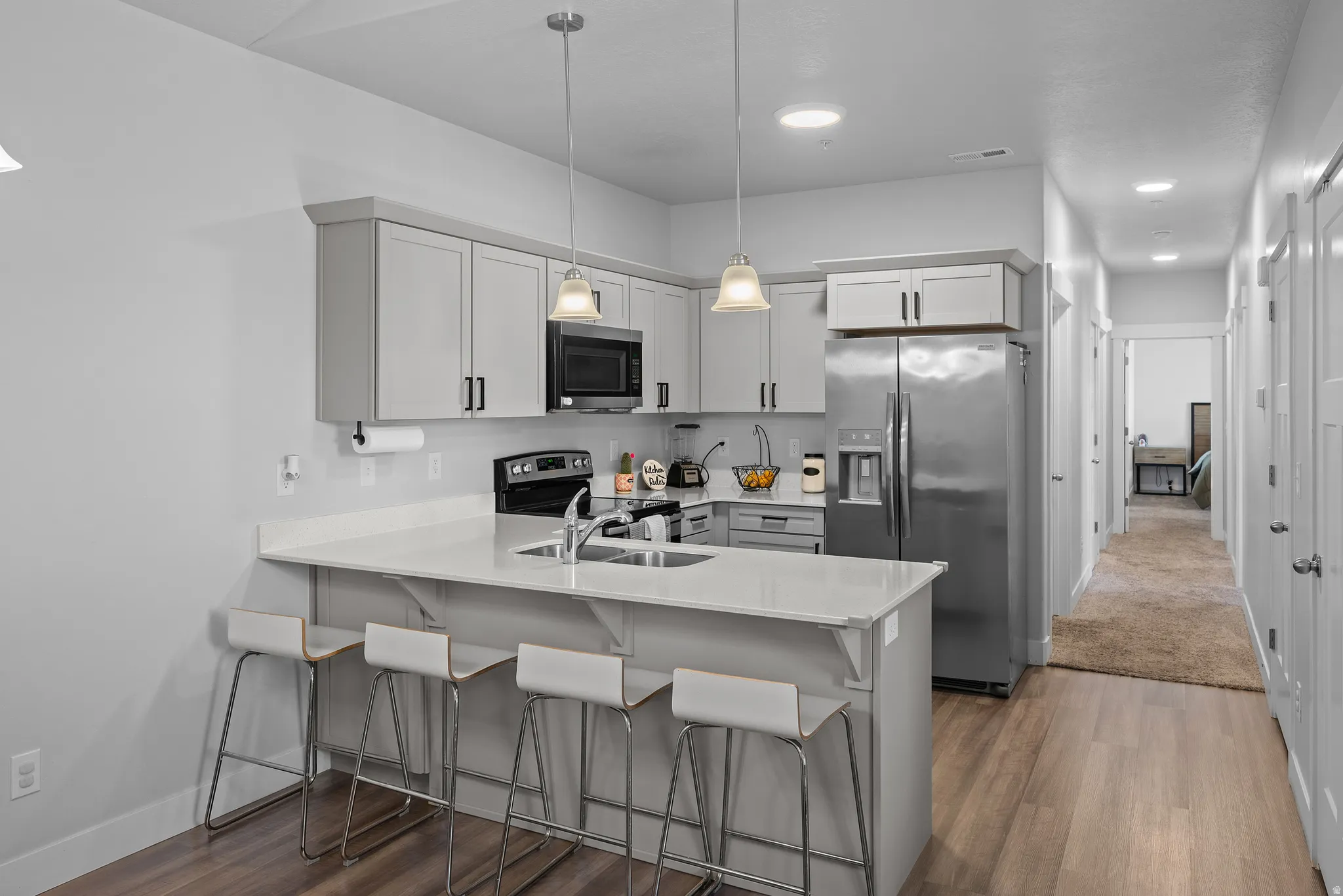 Modern kitchen featuring stainless steel appliances, white cabinetry with hardware accents, and white quartz countertops