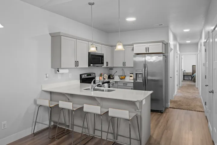 Modern kitchen featuring stainless steel appliances, white cabinetry with hardware accents, and white quartz countertops