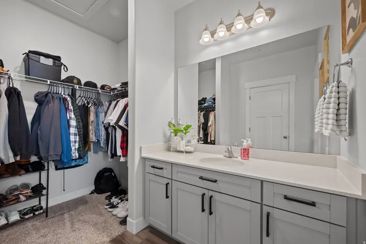 Spa-inspired primary bathroom featuring a gray vanity with black hardware, white quartz countertop, and an expansive framed mirror illuminated by pendant lighting