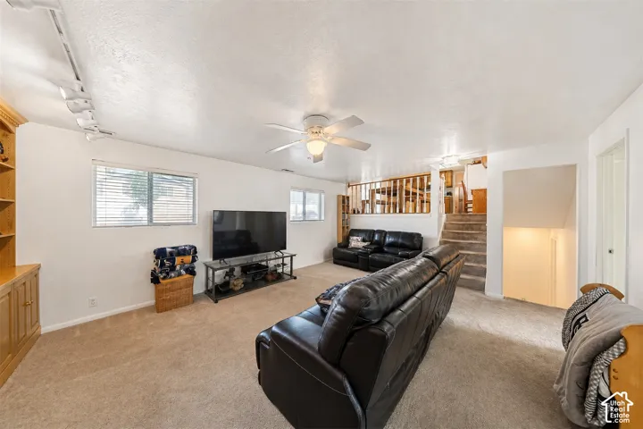 Carpeted living area featuring multiple windows, a ceiling fan, and built-in cabinetry