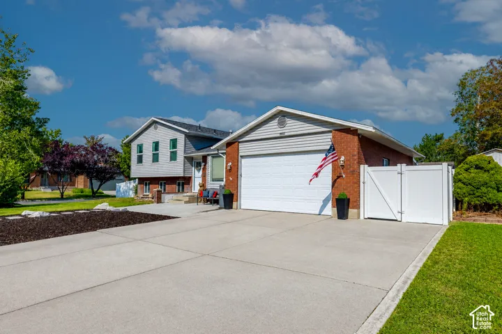 Contemporary split-level residence featuring brick and siding exterior, an attached two-car garage, and a concrete driveway