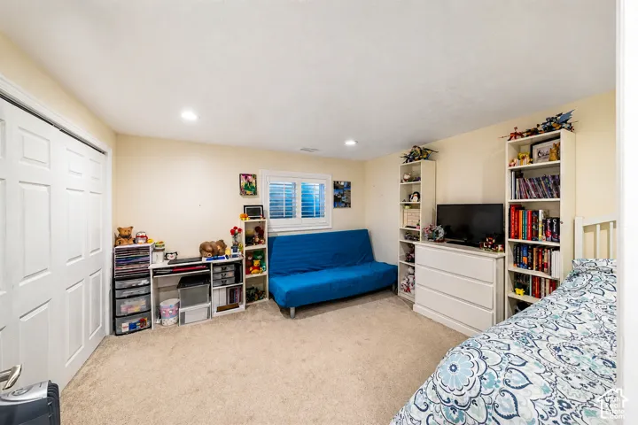Carpeted room featuring a double-door closet, recessed lighting, and a window with plantation shutters