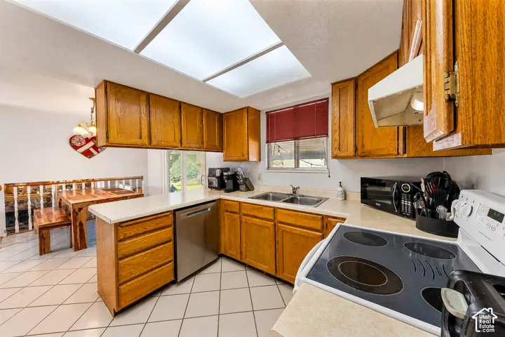 Functional kitchen featuring wood cabinetry, white countertops, stainless steel dishwasher, and a dual basin sink