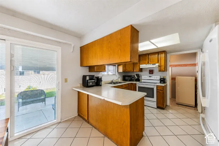 Kitchen featuring wood cabinetry, light-toned countertops, tile flooring, and a stainless steel range with overhead microwave