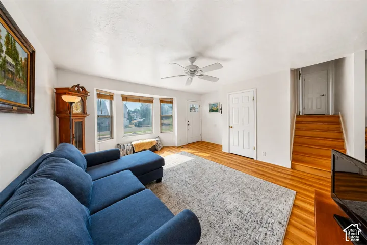 Bright living area featuring wood-finish flooring, a ceiling fan, and white trim throughout