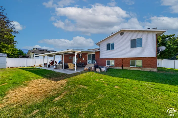 Expansive backyard featuring a covered patio, a white vinyl privacy fence, and a storage shed