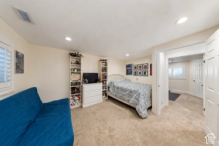 Spacious secondary bedroom featuring neutral carpet flooring, abundant natural light from multiple windows, and generous closet storage with built-in shelving