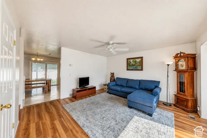 Spacious room featuring wood-finish flooring, light-toned walls, and a ceiling fan