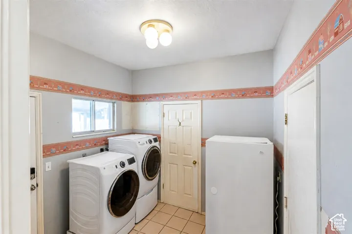 Dedicated laundry space featuring ceramic tile flooring, a window providing natural light, and a ceiling-mounted light fixture