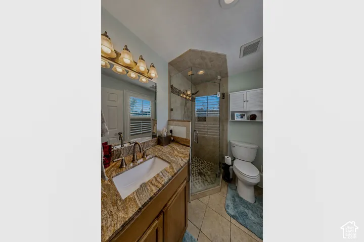 Bathroom featuring a walk-in shower with glass enclosure, a single vanity with a stone countertop, a rectangular undermount sink, and a multi-bulb light fixture