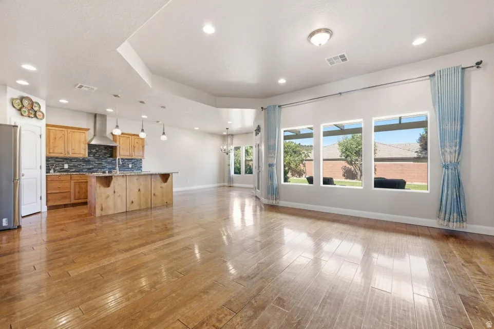 Open-concept living area featuring wood-finish flooring, recessed lighting, and a kitchen island with pendant lighting