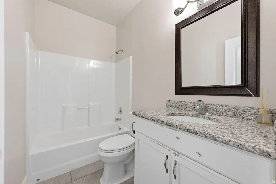 Spa-inspired bathroom featuring a white vanity with dual-sink granite countertop, framed mirror with bronze hardware, and a white subway tile shower-tub combination