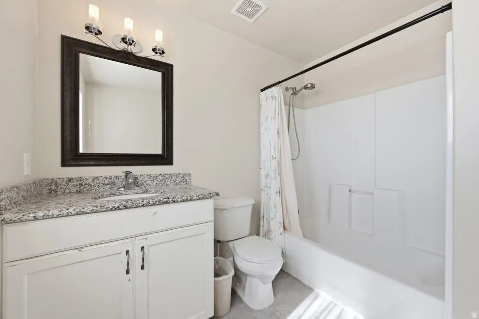 Contemporary bathroom featuring a white vanity with dual-sink granite countertop, framed mirror with integrated lighting, and a clean-lined bathtub/shower combination with white subway tile surround and chrome fixtures