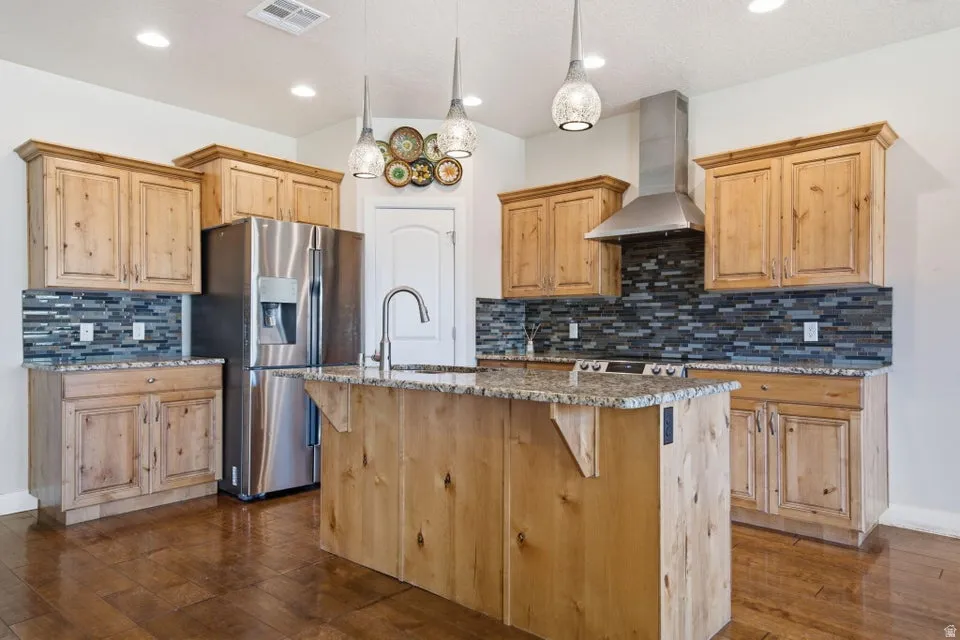 Gourmet kitchen featuring natural wood cabinetry, stainless steel appliances including a French-door refrigerator, and a large center island with wood-finish base