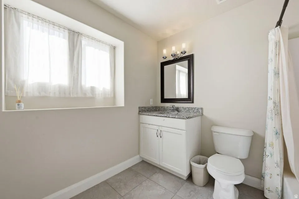 Bright and functional bathroom featuring a white vanity with dual-door cabinetry, granite-style countertop, and an integrated sink