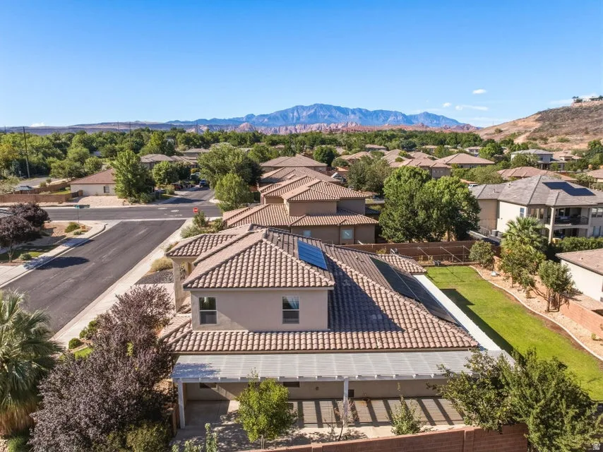 Elegant Mediterranean-inspired residence showcasing a striking clay tile roof with geometric patterning, situated on a manicured lawn with mature landscaping